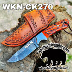 Orange leather knife sheath with stamped tooling sits on a tree trunk beside a blue Damascus-style blade; promotional logo and contact at wkcutlery9@gmail.com