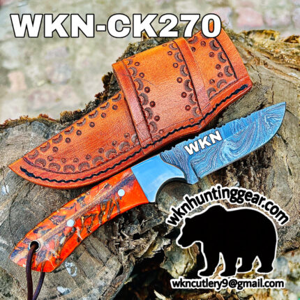 Damascus-pattern knife with an orange tooled leather sheath resting on a log; large 'WKN' on blade.