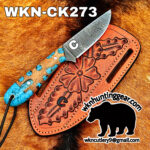 Damascus fixed‑blade knife with turquoise inlay on a brown leather sheath, set on fur background; model WKN-CK273, with huntinggear logo and a black elephant silhouette.