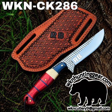 RB branded fixed-blade knife with a patterned steel blade and red-blue handle beside a brown leather sheath on a tree stump; outdoors.