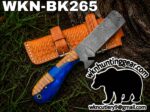Damascus fixed-blade knife with a blue and wood handle resting on a brown leather sheath outdoors; labeled WKN-BK265 with the wk hunting gear logo and bear graphic in the corner.