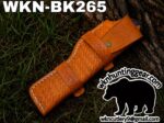 Brown tooled leather knife sheath on grass, model WKN-BK265, with WKNCutlery logo watermark nearby.