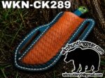 Blue-edged leather knife sheath with an orange tooled center and a green handle peeking out; watermark reads WKNC Hunting Gear with a bear logo.