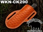 Leather woven knife sheath on dirt and grass with a knife handle peeking out; branding text and bear logo watermark from wk hunting gear in the image.