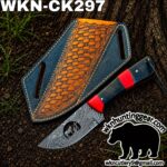Damascus-pattern hunting knife with red spacer next to a blue leather sheath on dirt, outdoor setting with watermark text in the corner.