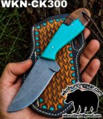 Hunting knife with a turquoise handle resting on a patterned leather sheath outdoors.','Turquoise-handled knife displayed on a decorative leather sheath with turquoise studs.','A fixed-blade knife with a bright turquoise handle placed on a textured leather sheath with turquoise accents.','Close-up of a turquoise-handle knife on its leather sheath, outdoors (brand watermark visible).','Outdoor hunting knife shown on its patterned sheath, featuring a teal handle and rugged leather details.