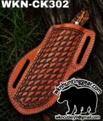 Leather woven knife sheath with white stitching, resting on a tree trunk; labeled WKN-CK302.