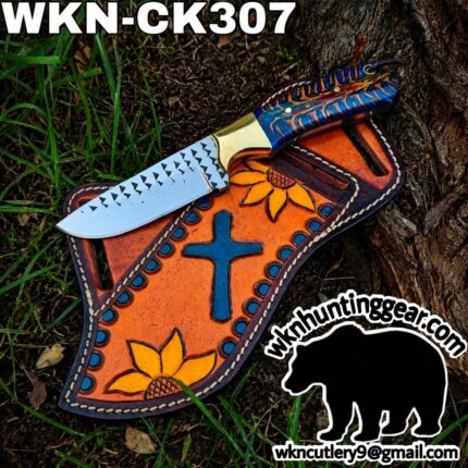 Fixed-blade knife with a blue, orange-patterned handle laid across an orange leather sheath featuring sunflowers, outdoors on grass; watermark and contact info visible.