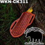 Leather knife sheath with a woven red pattern resting on a tree trunk; yellow blade grip peeks from the top, branding shows wknhuntinggear.com and a bear silhouette sticker.