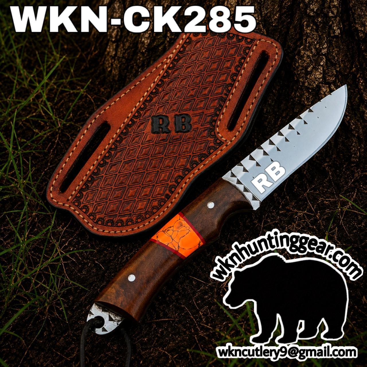 Knife with carved wooden handle and silver blade labeled 'RB', resting beside a brown leather sheath with 'RB' stamp, outdoors.