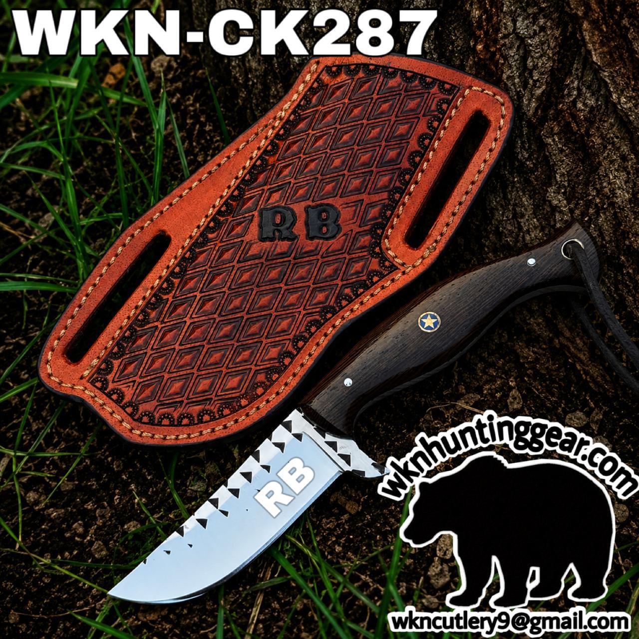 Fixed-blade knife with a dark wooden handle and a silver blade marked RB, shown with a patterned brown leather sheath outdoors on soil and grass.