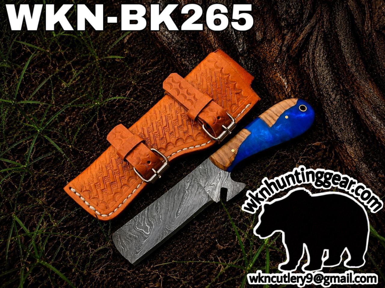 Damascus fixed-blade knife with a blue wooden handle beside an embossed brown leather sheath on dirt, wkncutlery.com logo visible.