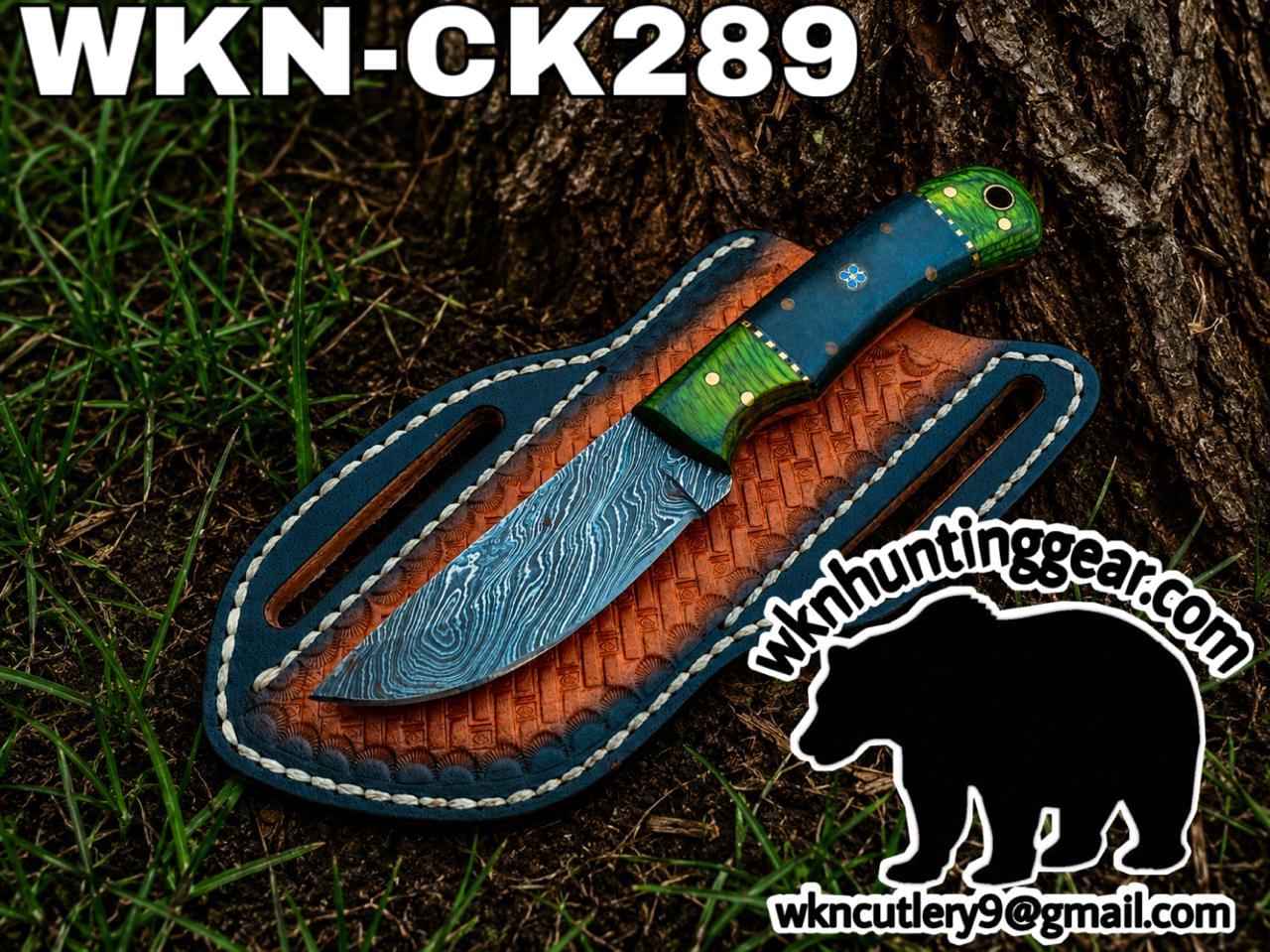 Custom hunting knife with blue damascus blade and green handle on a brown leather sheath, outdoors by a tree; watermark includes wknhuntinggear.com.