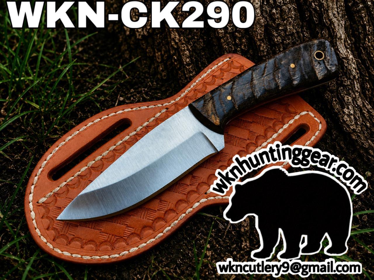 Fixed-blade knife with textured handle laid on a brown leather sheath outdoors; branding text WKN-CK290 appears above.