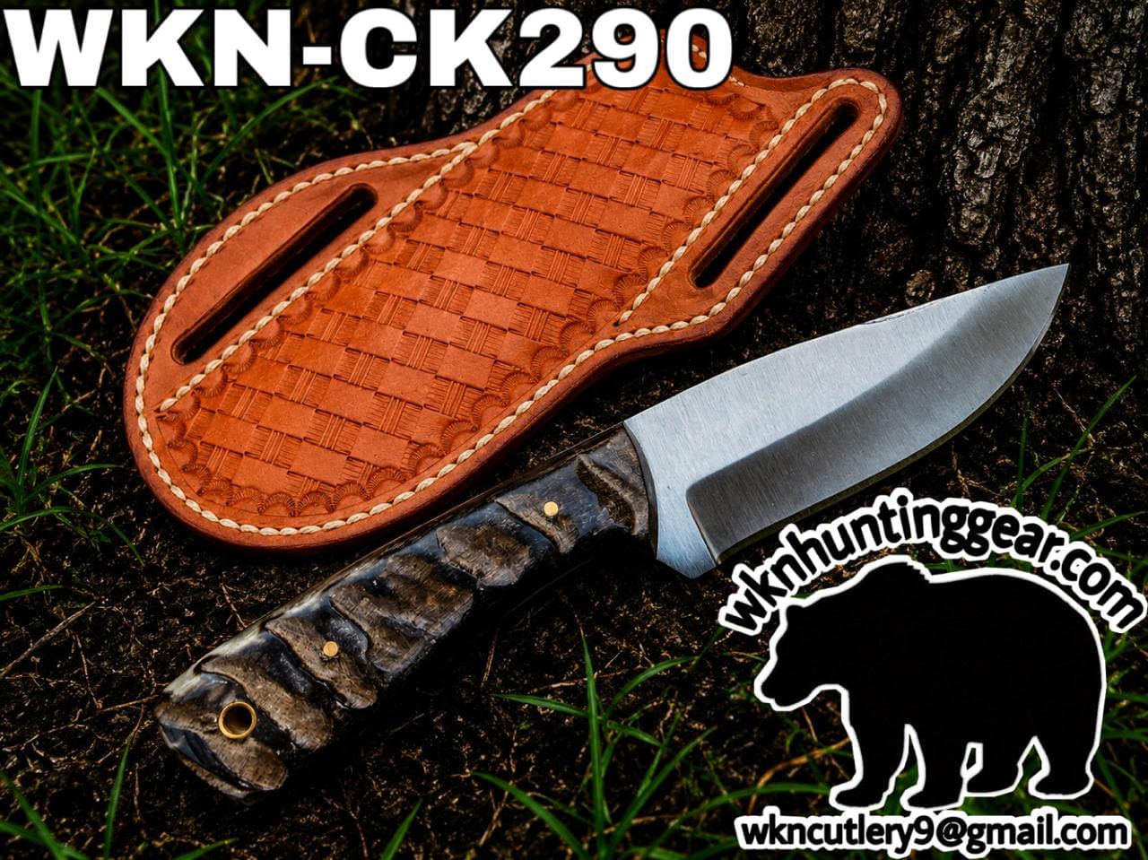 Hunting knife with a textured dark handle and bright steel blade beside a brown leather sheath outdoors on dirt, with branding text 'WKN-CK290' and a bear logo and email address in the corner.