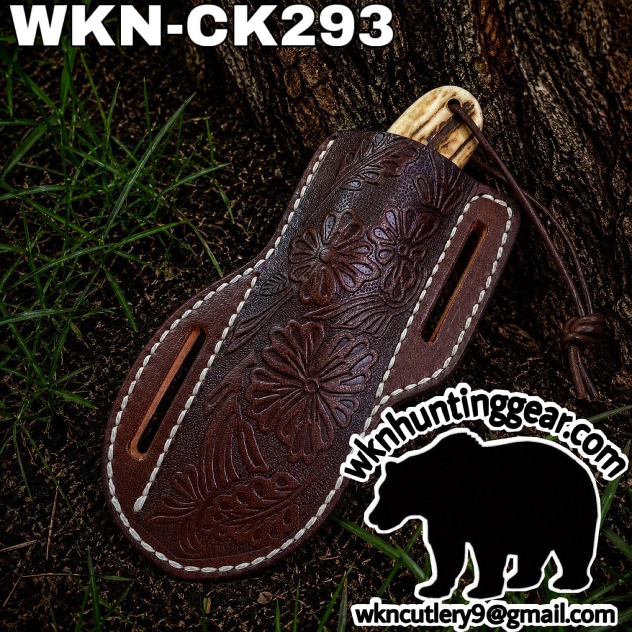 Brown tooled leather knife sheath with floral pattern, shown outdoors against a tree trunk; model WKN-CK293 and huntinggear logo are visible.