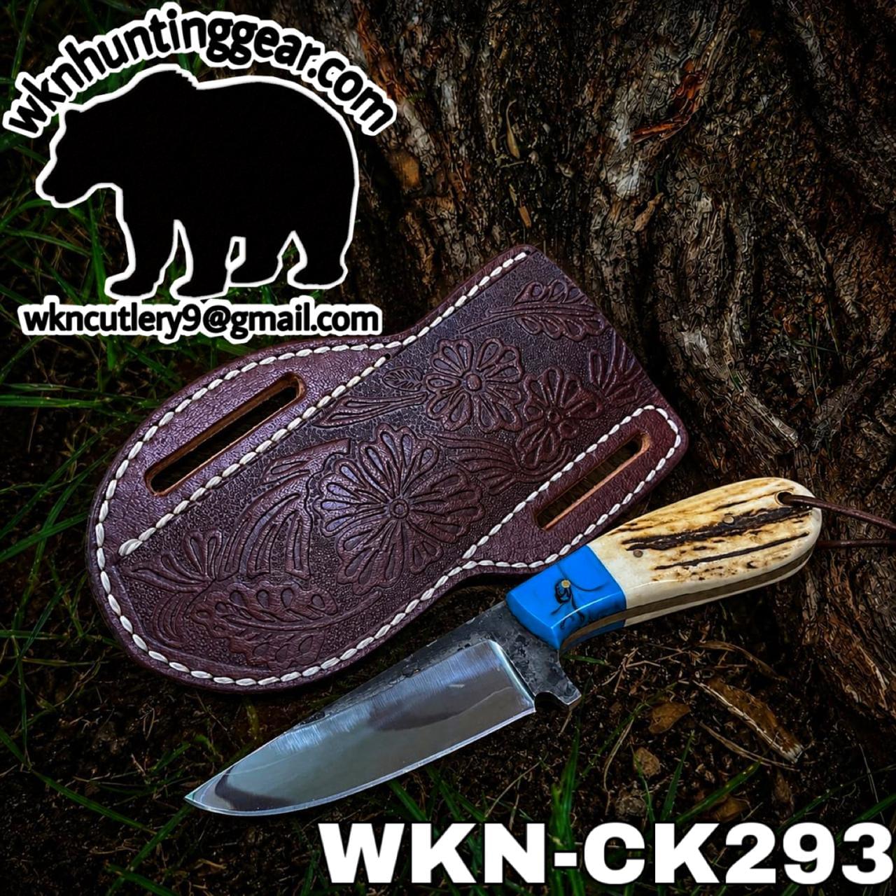 Fixed-blade knife with an antler handle lay beside a floral-carved leather sheath on a tree trunk; watermark wknhuntinggear.com and code WKN-CK2933.