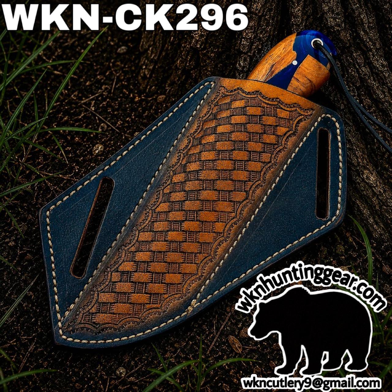 Blue leather knife sheath with a decorative brown center panel and an orange-wood handle peeking out, laid on dirt outdoors; branded WKN hunting gear with a bear logo and contact text in the corner.