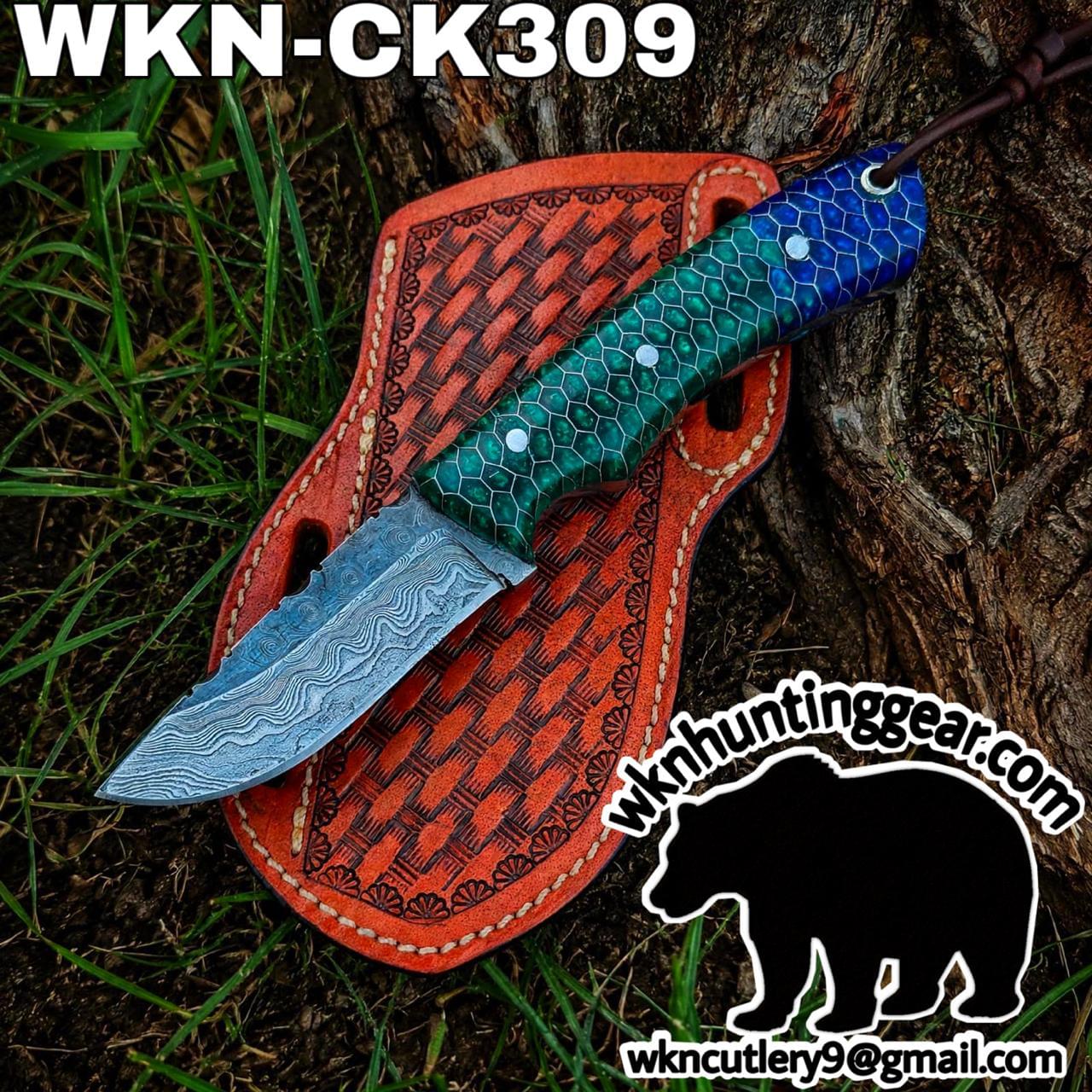 Fixed-blade knife with Damascus-pattern blade and green hexagonal-scale handle on an orange leather sheath outdoors.