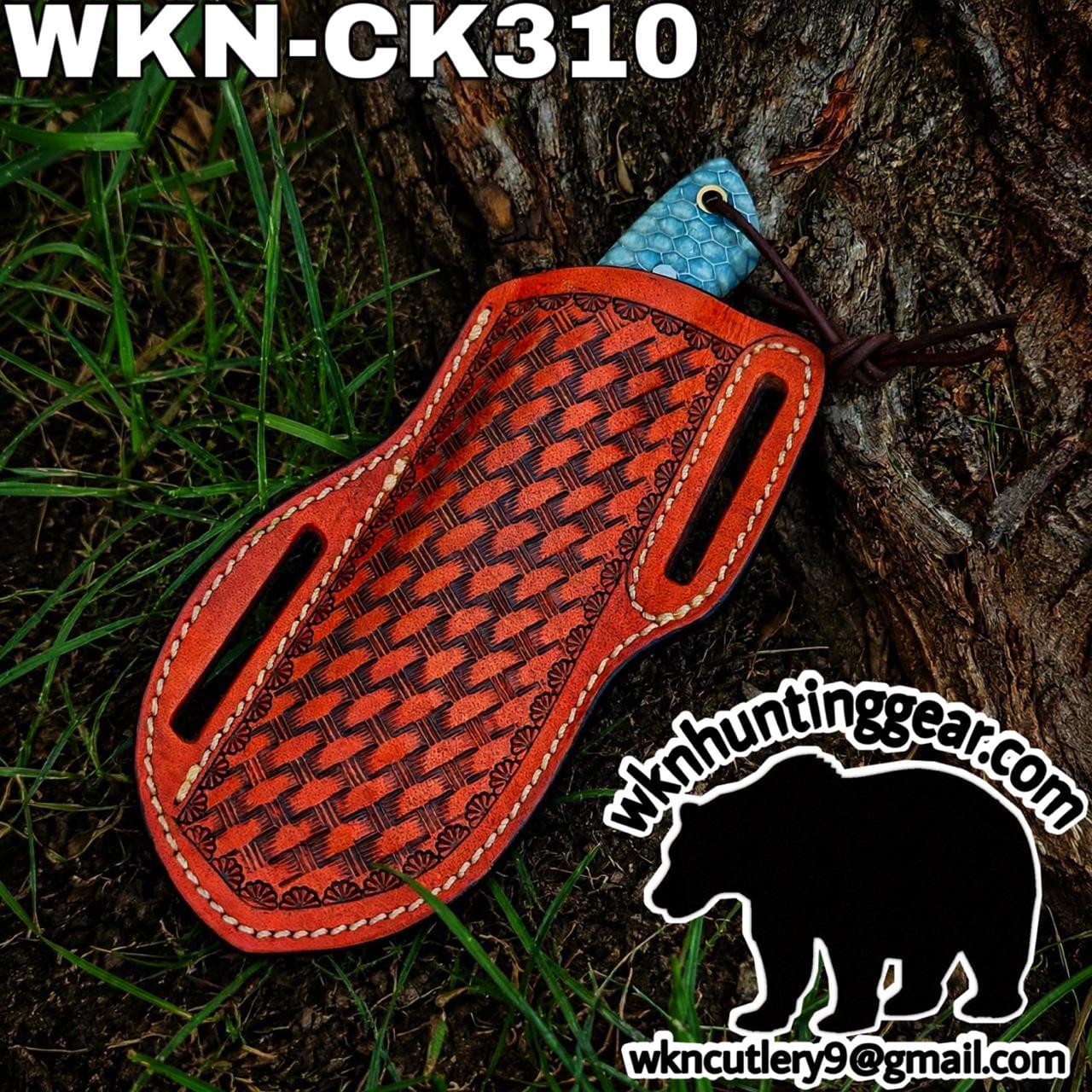 Orange tooled leather knife sheath with a blue handle resting on a tree trunk; watermark logo and bear silhouette in the lower right corner