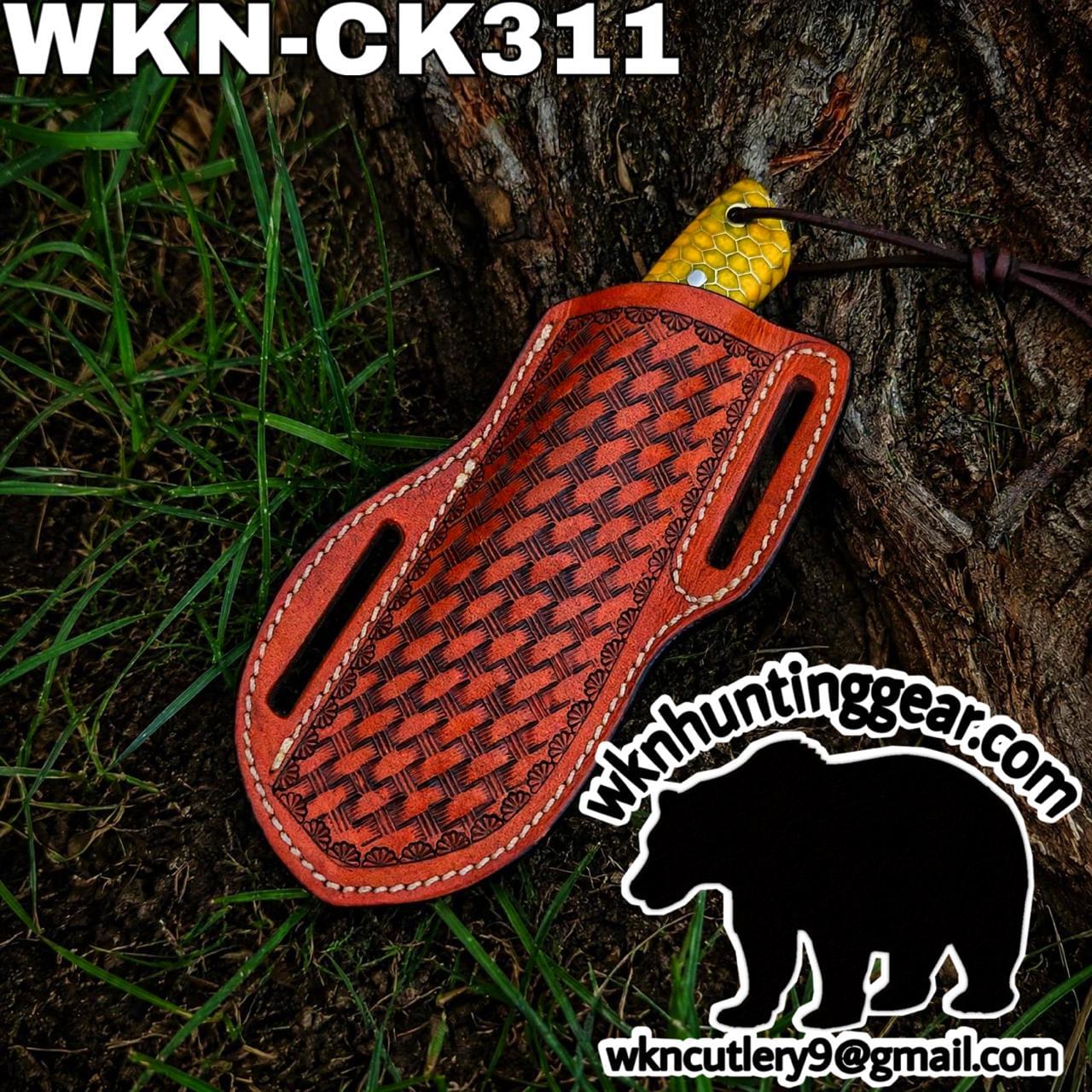 Leather knife sheath with a woven red pattern resting on a tree trunk; yellow blade grip peeks from the top, branding shows wknhuntinggear.com and a bear silhouette sticker.