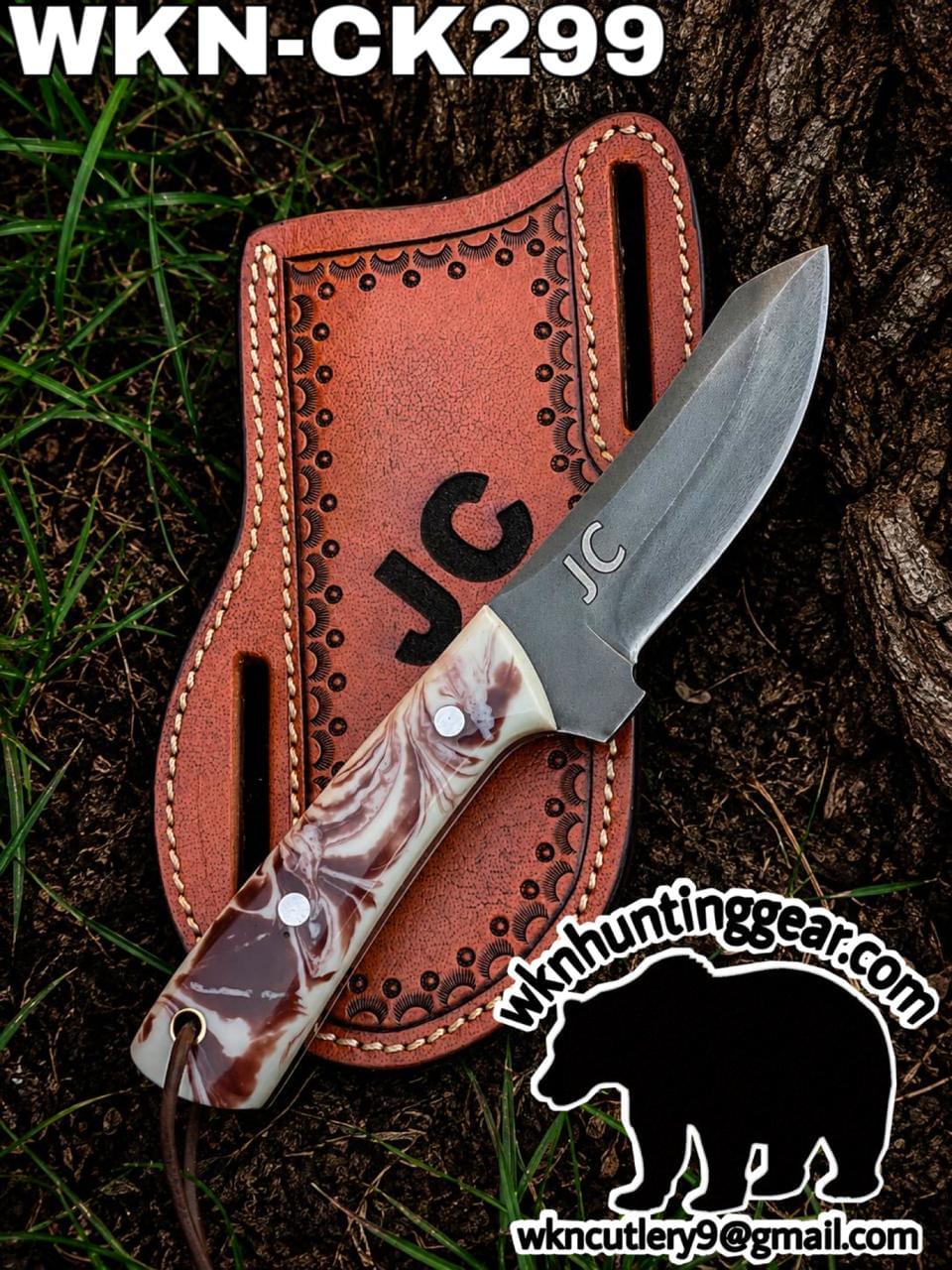 Fixed-blade hunting knife with a marbled handle laid on a brown tooled leather sheath outdoors; model WKN-CK299 visible atop the sheath.